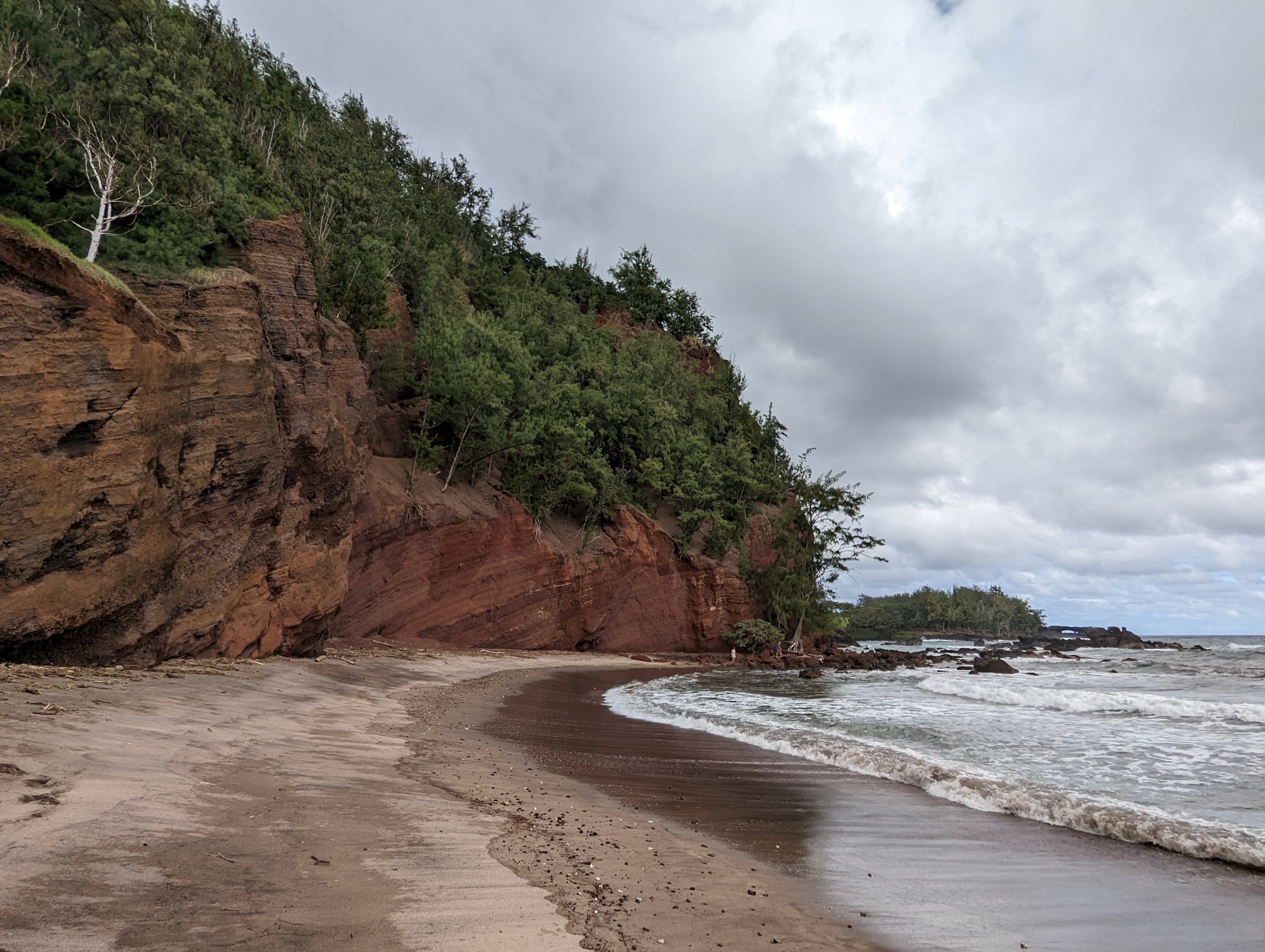 A picture of a tall forested cliff above a beach on the southeast coast of Maui.